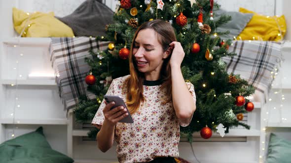 Beautiful girl sits against the background of a Christmas tree on New Year's Eve