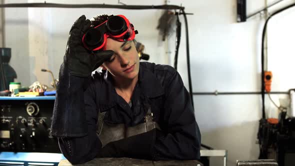 Female welder leaning in workshop alt