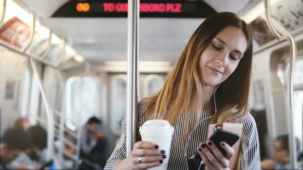 Happy Relaxed Beautiful Millennial Girl Stands in Subway Train Looking at Smartphone Using alt