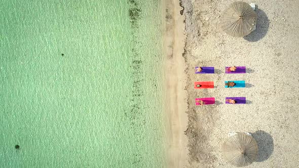 Aerial view of yoga group on mats on beach with parasols. alt