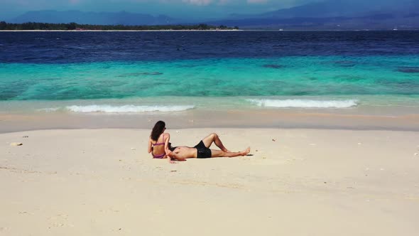 Guy and girl relax on tranquil seashore beach break by blue ocean and white sandy background of Gili alt