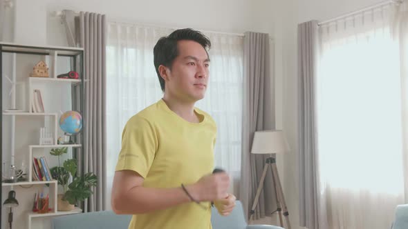 Asian Man Running On A Treadmill At Home alt