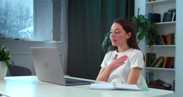 Energetic Girl Speaks While Video Conference Call Sitting Indoor at Home Table alt