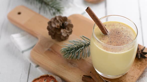 Homemade traditional Christmas eggnog drink in a glass with ground nutmeg and cinnamon