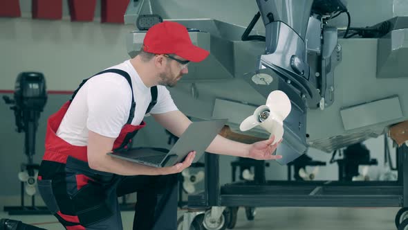 Serviceman with a Laptop Is Checking Boat's Engine alt