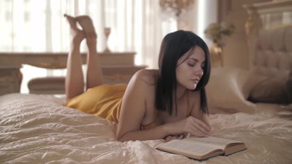 Beautiful Caucasian Woman Lying on the Bed and Reading a Book