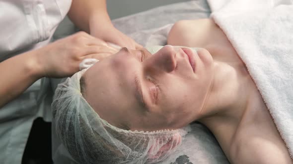 Female Cosmetologist Hands Clean the Face of a Young Man with a Napkin