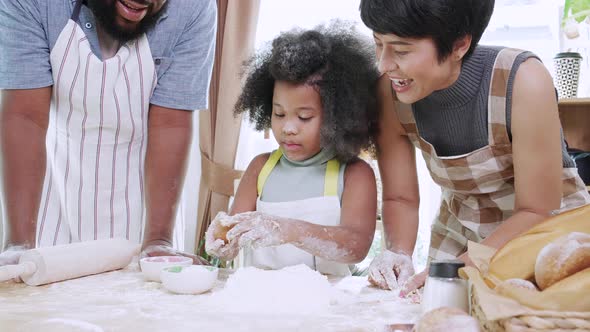 Close up of Happy African American girl thresh dough with parents together