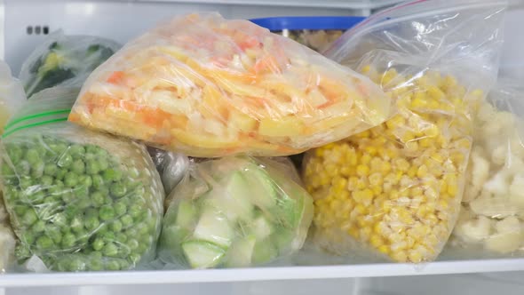 Female Hands pulls frozen Bell pepper out of the fridge.