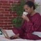 Concentrated Young Woman Drinking Morning Coffee in Bedroom Messaging Online Typing on Laptop