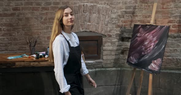 Portrait of Talented Innovative Pretty Female Artist with Brush and Her Canvas on Background alt