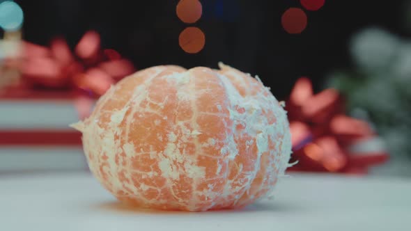 Peeled tangerine against the background of Christmas lights, the concept of new year and christmas.