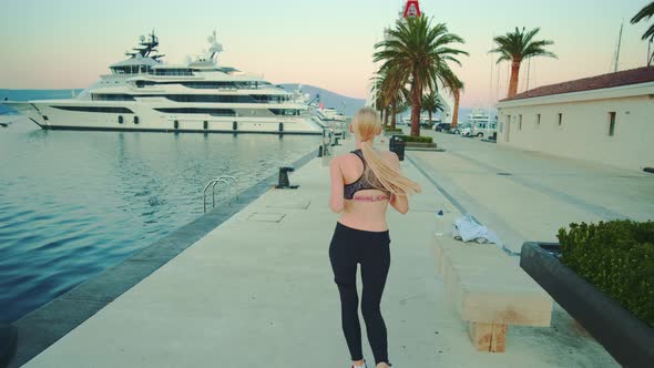Back View of Blonde Sport Woman Jogging in Port