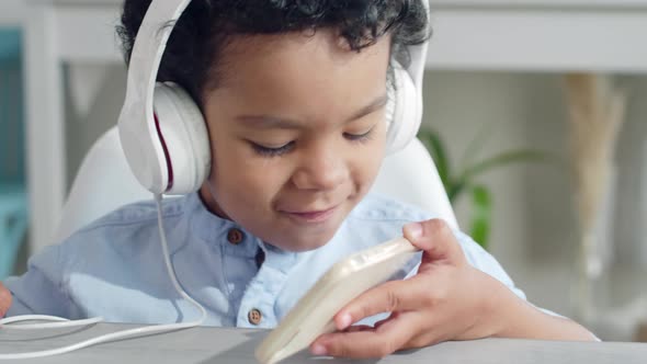 Little Boy in Headphones Enjoying Music on Smartphone