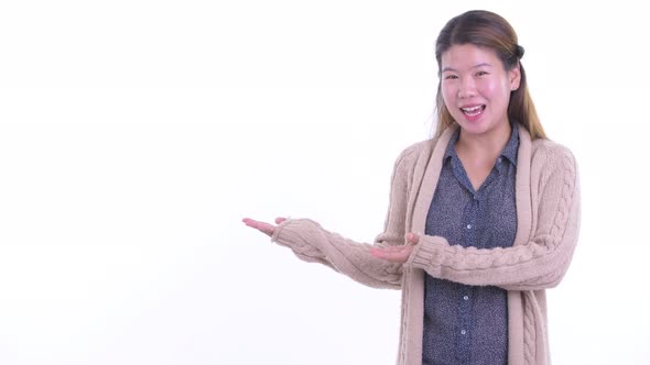 Happy Young Asian Woman Talking While Showing Something Ready for Winter alt