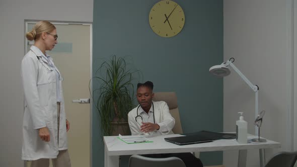 Mature Female Doctor Disputing with Young Male Physician Indoors alt