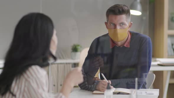 Colleagues Communicating Through Glass in Office alt