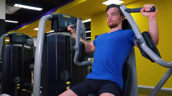 A Young Fit Man Trains on a Machine in a Gym - Closeup alt