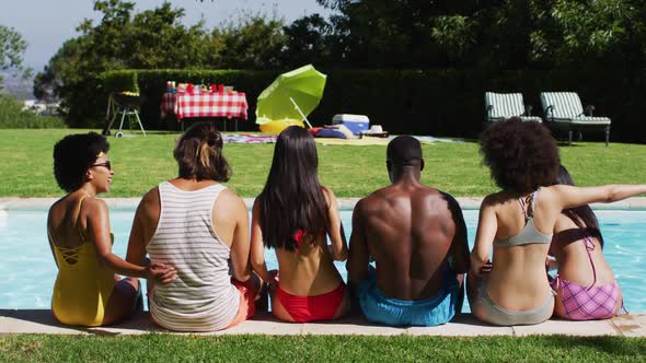 Diverse group of friends sitting in a row at a pool party alt