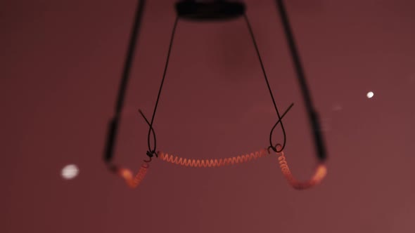 The Tungsten Filament in a Glass Lamp Closeup in Slow Motion on Red Background alt