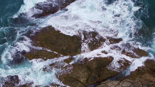 Aerial view top down of big waves crashing on rocks in dark blue ocean. Beautiful sea waves water alt