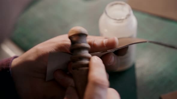 The Process of Manufacturing a Leather Wallet Handmade. A Craftsman Grinding a Piece of Leather