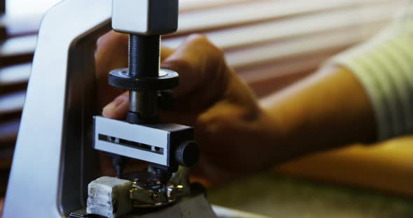 Horologist repairing a watch on a machine alt