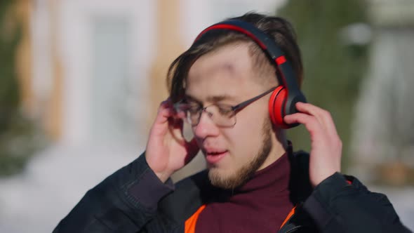 Closeup Portrait of Absorbed Excited Young Caucasian Man in Eyeglasses Enjoying Music in Headphones alt