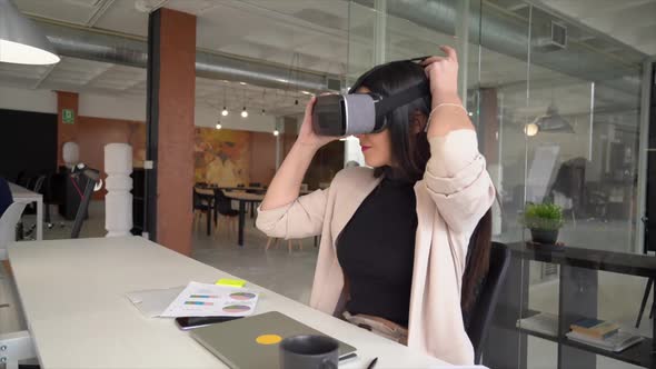 Businesswoman sitting at desk using virtual reality simulator alt
