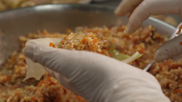 The Cook Holds the Stuffed Cabbage and Pours a Spoonful of Minced Meat Into It