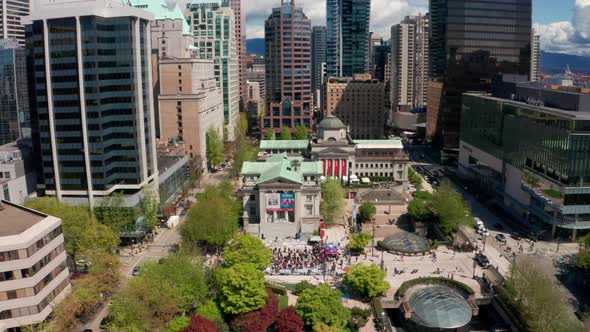 Drone shot pulls away from crowd of people on the steps of Vancouver Art Gallery in Robson Square in alt