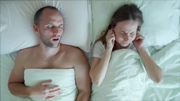 A Disgruntled Frustrated Young Woman Can't Sleep While Her Boyfriend Snores in Bed in the Bedroom alt