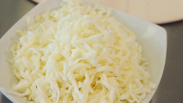 close up of freshly shredded mozzarella in a bowl. natural ingredients for pizza. slow motion alt