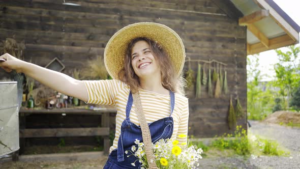 Lady in Hat with Flowers in Bag Waters Plants Near House