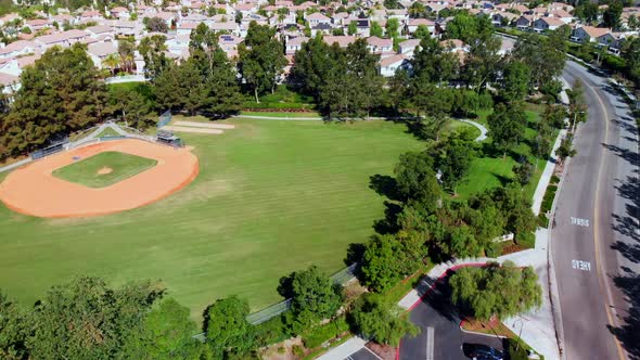 Aerial drone pan over and by a baseball field at a community park in the suburbs. alt