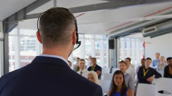 Male speaker with headset microphone addressing the audience at a business seminar alt