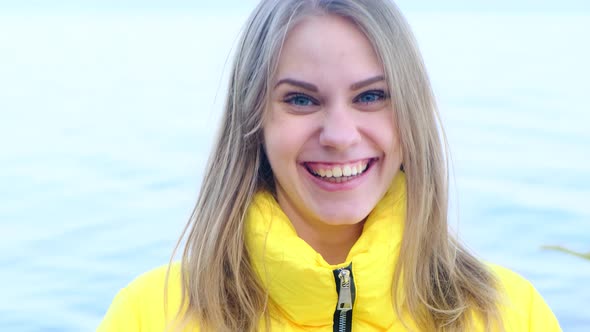 Portrait of a Young Happy Laughing Woman in a Yellow Jacket Looking at the Camera Against the alt