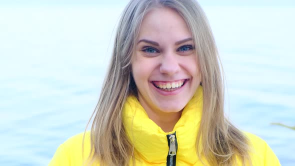 Portrait of a Young Happy Laughing Woman in a Yellow Jacket Looking at the Camera Against the