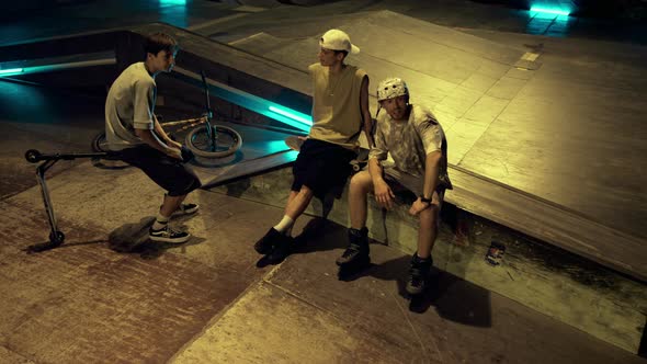 Relaxed Friends Communicating Together in Skate Park with Graffiti Wall alt