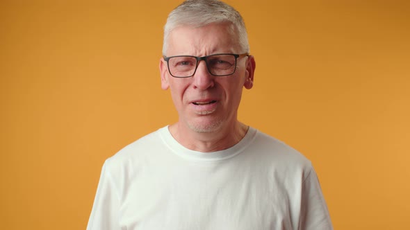 Sad Senior Man Starting to Cry Over Yellow Background