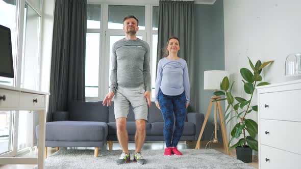 Caucasian Couple is Doing Jumping Jacks Exercise at Home in Cozy Bright Room Slow Motion alt