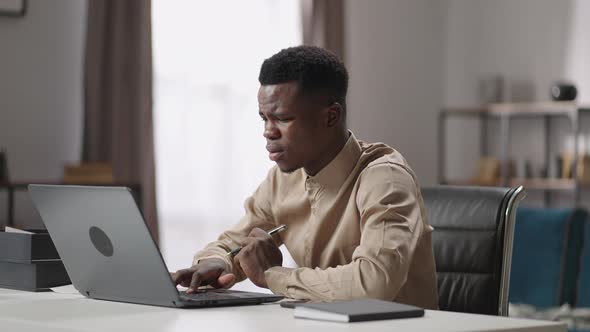 Sad Afroamerican Man is Using Laptop at Home Office Finding Mistake and Error of Program Grimacing alt