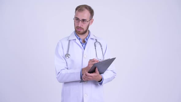 Happy Bearded Man Doctor Talking While Holding Clipboard