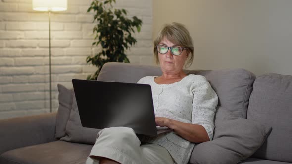 Surprised Woman On Sofa With Laptop. Woman Browses The News Or Some Other Information Via The alt
