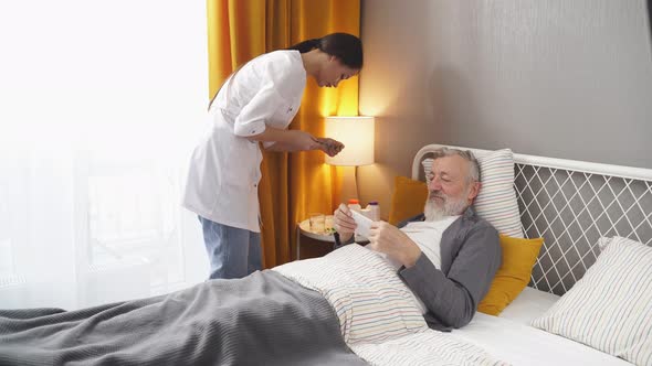 Young Nurse Cares for an Elderly Man Checks the Pills That Need to Be Drunk