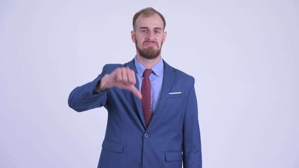 Stressed Bearded Businessman Pointing at Camera and Giving Thumbs Down