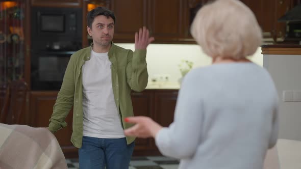 Portrait of Irritated Handsome Man Arguing with Senior Woman Gesturing and Yelling alt