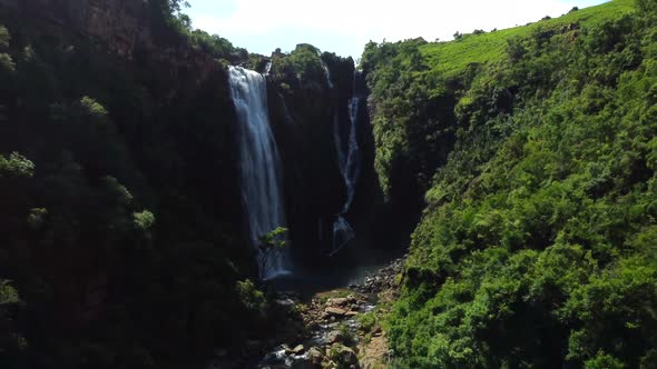 Drone shot of Mpumalanga in South Africa - drone is reversing from a waterfall in a natural valley. alt
