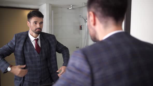 Handsome Man Putting on Suit Jacket in Bathroom alt