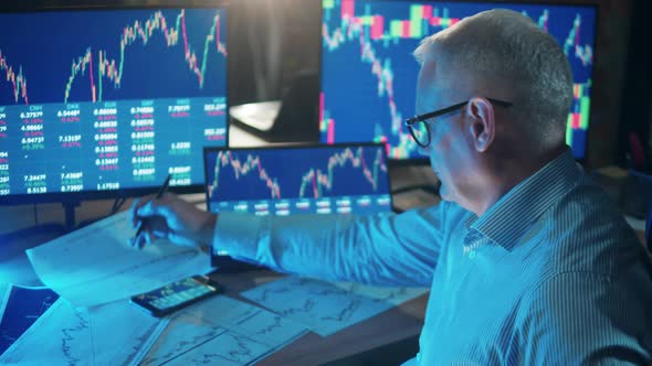 Male Stockbroker is Making Notes is the Data Reports alt